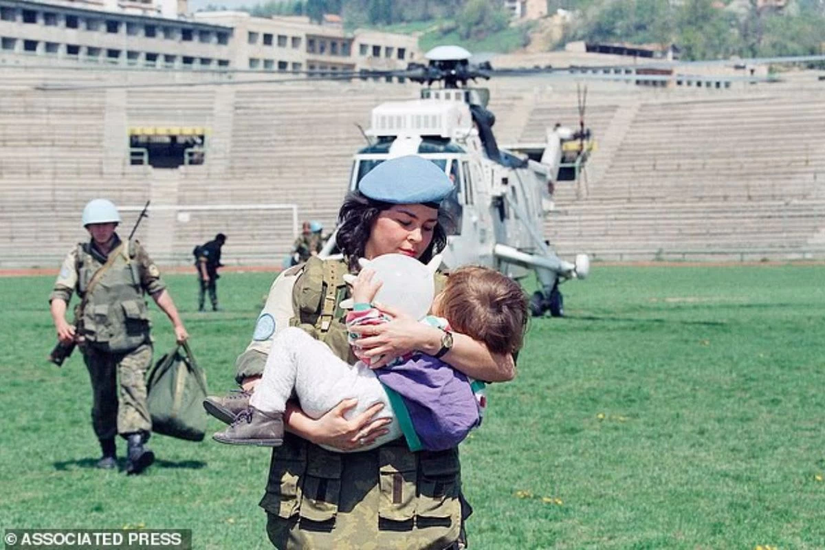 Әскери қызметкер баланы көтеріп барады