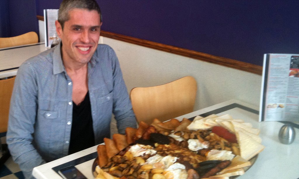 PIC FROM CATERS NEWS - (PICTURED Robert Pinto who travelled 125 miles to tackle this giant breakfast.) - A gigantic meal dubbed the Kidz Breakfast because it weighs the same as a SMALL CHILD has been EATEN. The whopping brekkie is 6,000 calories, the equivalent to TWO christmas dinners or twelve Big Macs, and weighs a belt buckling 9lbs. Jesters Diner in Southtown, Great Yarmouth are currently flogging the mammoth feast for £15 or free to anyone who can finish it. And now someone has literally stepped up to the plate...and cleared it, in an amazing 26 MINUTES. The Kidz Breakfast consists of 12 bacon rashers, 12 sausages, six eggs, four slices of black pudding, four slices of bread and butter, four slices of toast, four slices of fried bread, beans, tomatoes, mushrooms, saute potatoes and an EIGHT egg cheese and potato omelette. The jumbo breakfast has now been polished off by surprisingly slim diner Robert Pinto who travelled 125 miles from his home in Rutland to tackle the tummy-busting tucker. SEE CATERS COPY