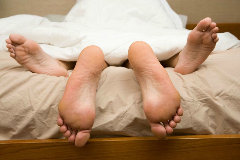 View-of-feet-of-couple-having-sex-in-bed