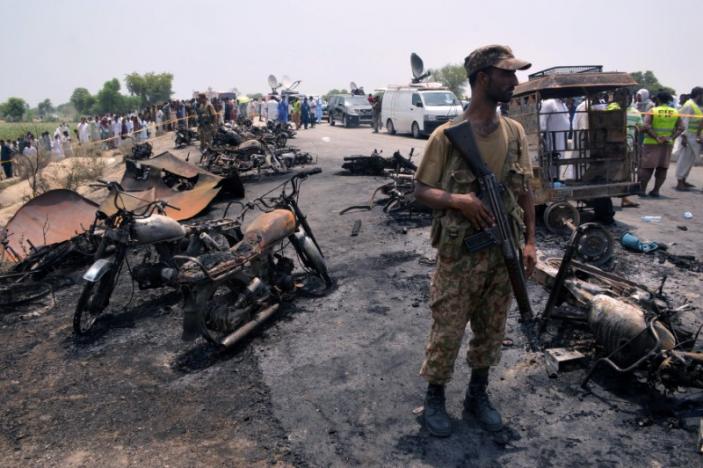 A soldier stands guard amid burnt out cars and motorcycles at the scene of an oil tanker explosion in Bahawalpur, Pakistan June 25, 2017. REUTERS/Stringer
