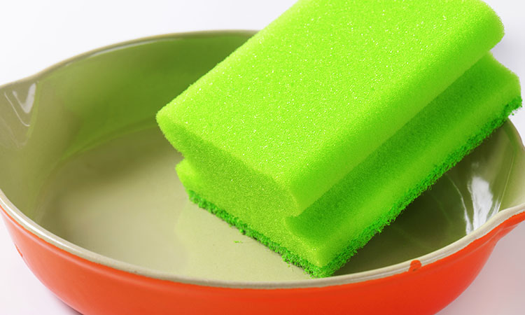 green kitchen sponge on ceramic baking dish